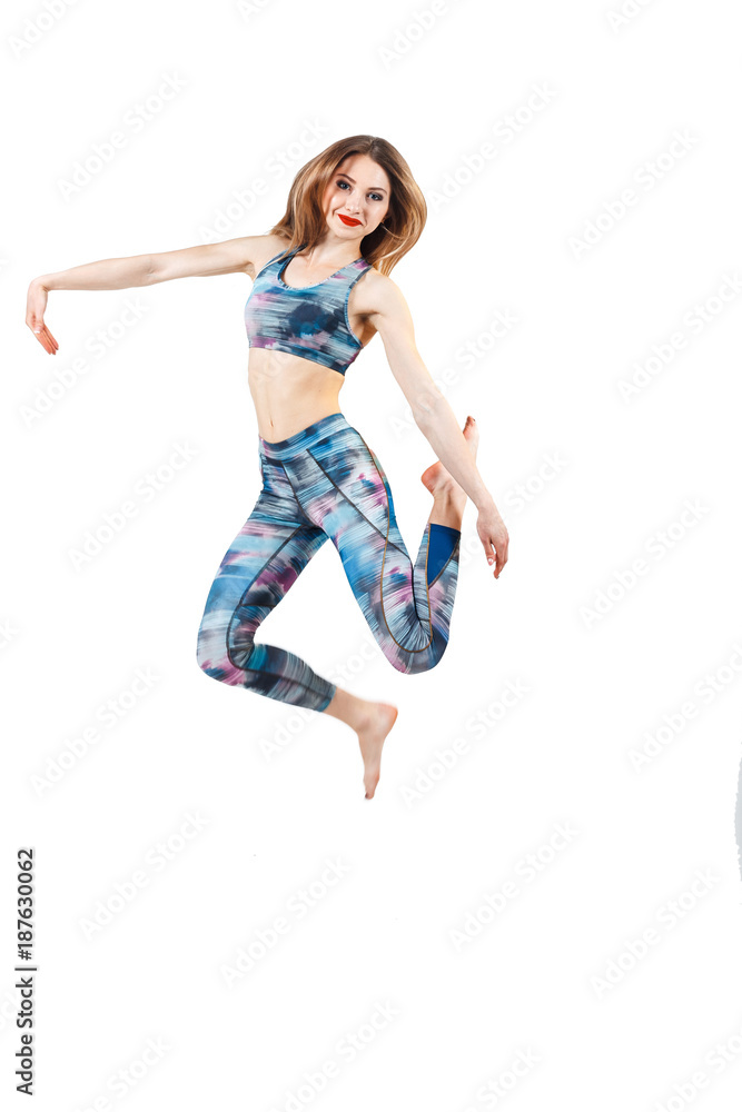 young beautiful woman in color-blue top and leggings jumping of joy. Young sporty fit emale model isolated on white background in full body.