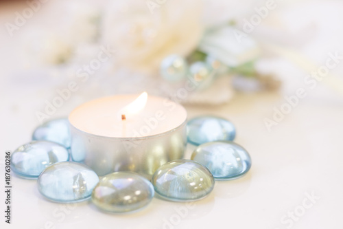 St. Valentine's Day concept with a burning white candle and decorative glass pebbles, close up, white background