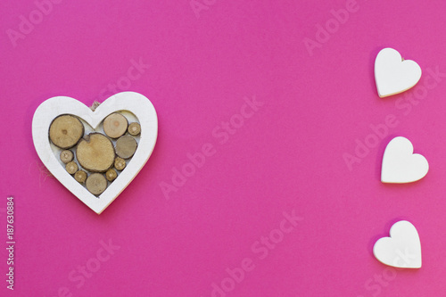 St. Valentine's Day or Anniversary concept pink background with wooden hearts, top view