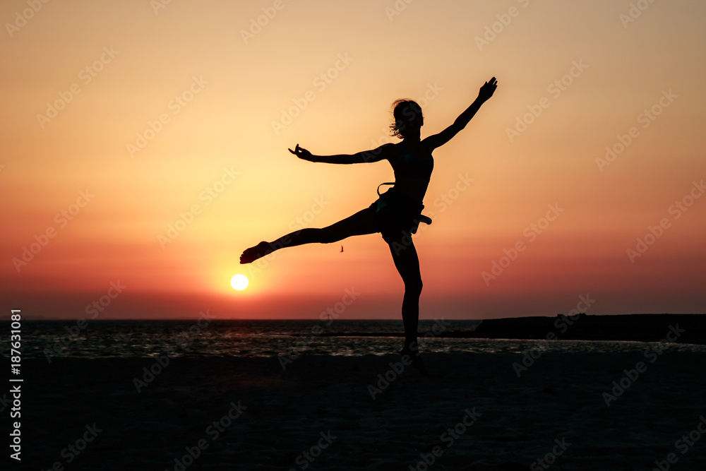Woman girl model with slim figure like ballet dancer silhouette on the sea background, orange sunset sky and sea background, Africa, Egypt. Red Sea. Awesome people and nature picturesque scenery