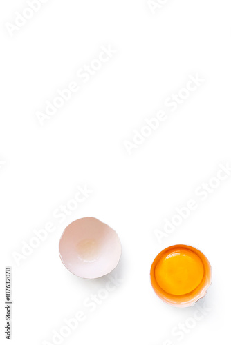 fresh brown organic chicken egg broken with yolk and egg white isolated on white background. Vertical composition. Top view