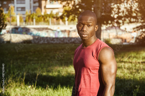 Portrait of a sexy young black man in urban park, wearing red sleeveless shirt