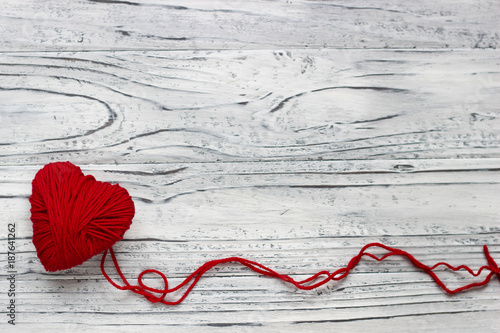 Heart in the form of a string of threads from which a red sweater knits. Valentines day concept.