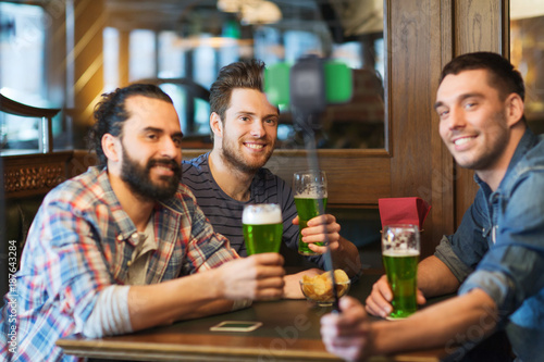 Photos friends taking selfie with green beer at pub