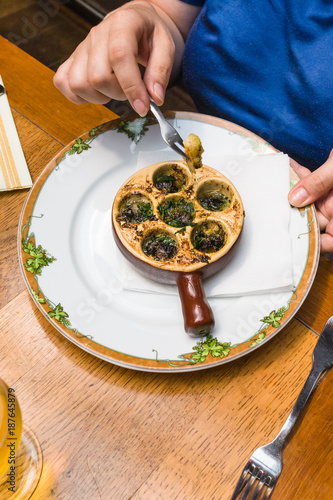 woman eats snails in burgundy style in Normandy