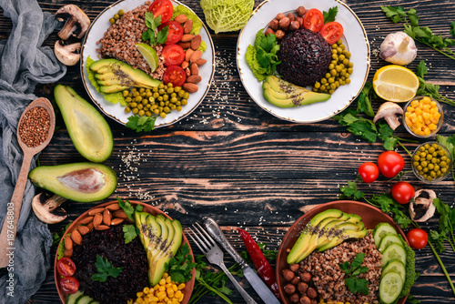 Healthy food. Black rice, buckwheat, avocado, cherry tomatoes, green peas and hazelnut. On a wooden background. Top view. Free space for your text.