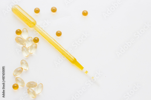 Natural cosmetics concept, vitamin oil capsules and a dropper, white background, close up