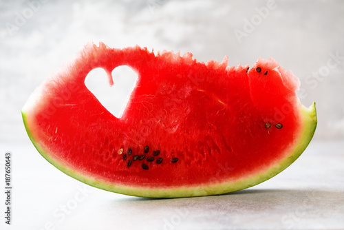 Piece of watermelon with heart shape on grey concrete background. Copy space. Flat lay. Greeting card  love concept. Valentine s Day