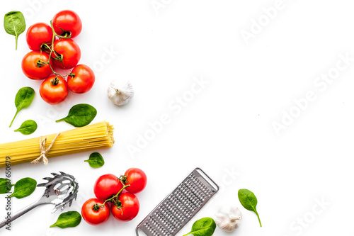 Preparing to cook pasta. Spaghetti, tomatoes, garlic, cheese grater, spoon for spaghetti on white background top view copy space