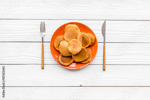 Homemade pancakes on orange plate. White wooden background top view copy space photo