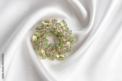 round brooch with gems isolated on a white silk