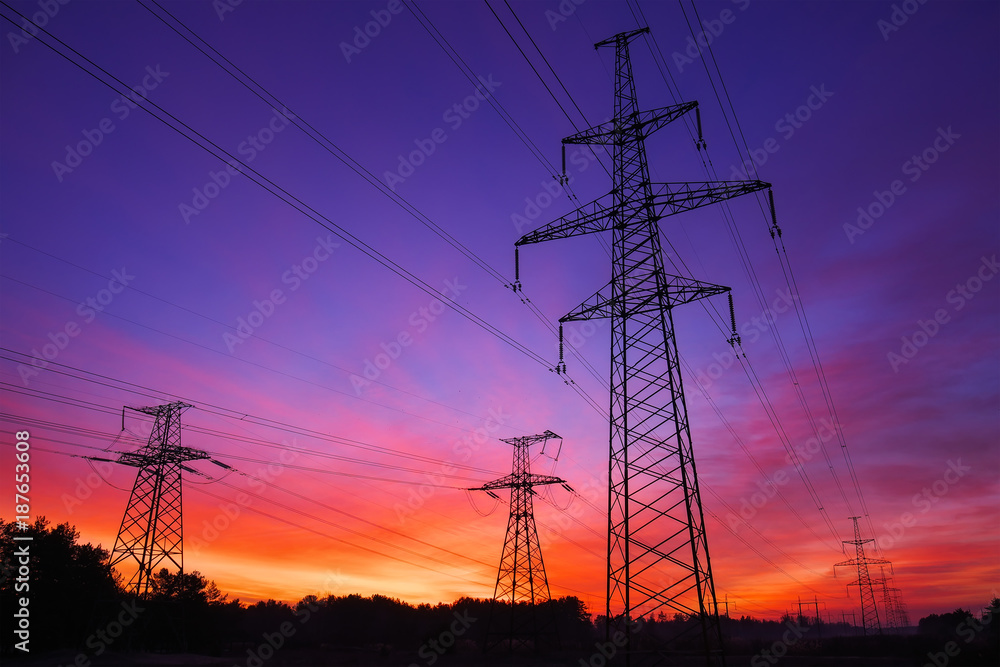 Fototapeta premium High-voltage power lines during fiery sunrise