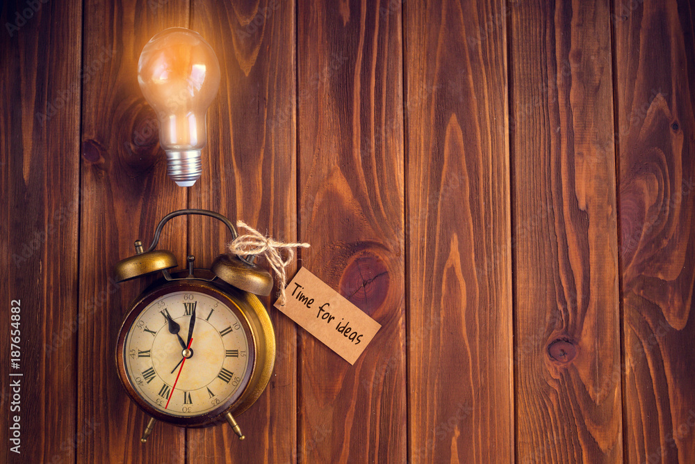 Alarm clock and a light bulb on a wooden background. Concept Earth Time  Stock-Foto | Adobe Stock