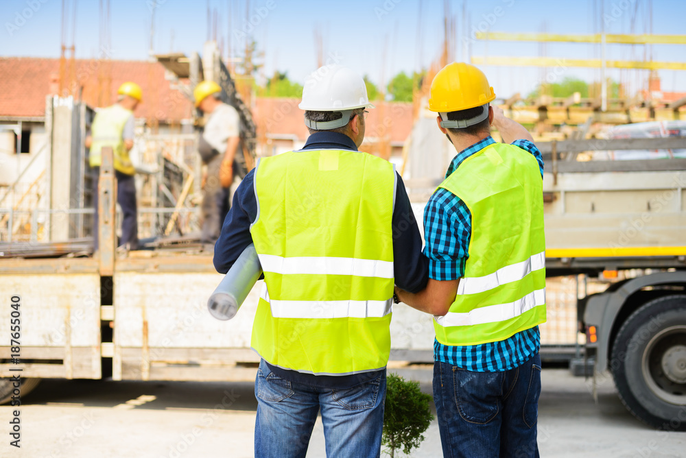 Workers in hardhat and green jacket posing on building site Workers in hardhat and green jacket posing on building site