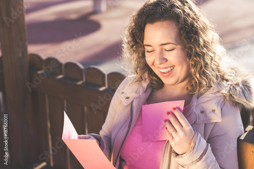Young beautiful woman reading a love letter on Valentines / Womens Day at the park.