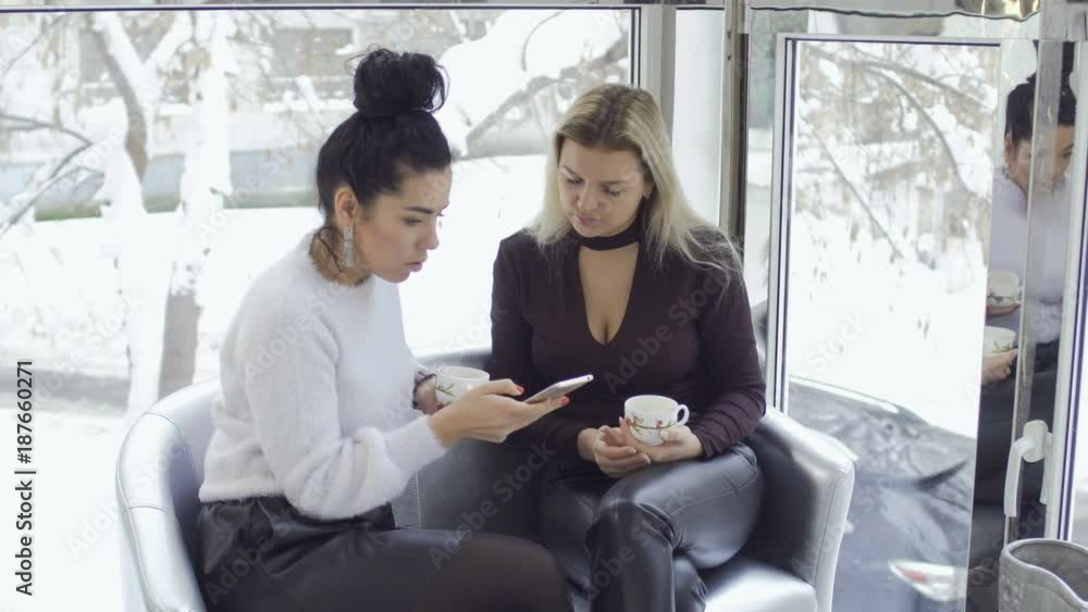 Attractive businesswomen dicussing something looking at phone Attractive businesswomen dicussing something looking at phone