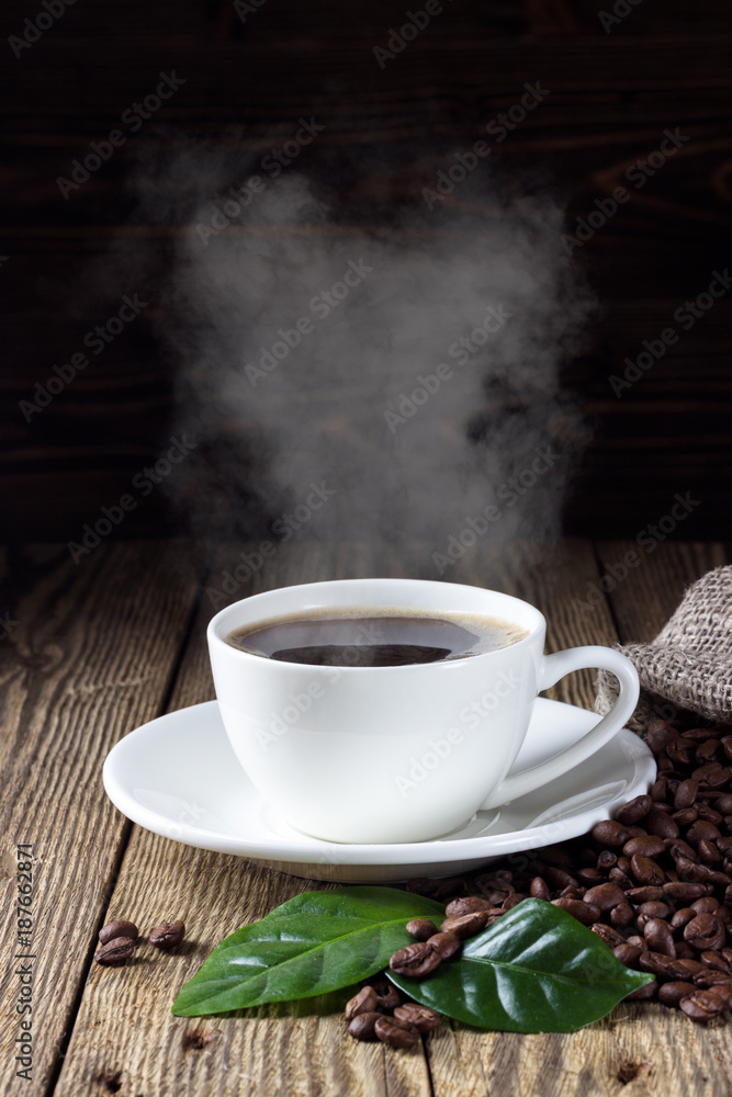 Cup of hot coffee with coffee beans and leaf on wooden bachground Cup of hot coffee with coffee beans and leaf on wooden bachground