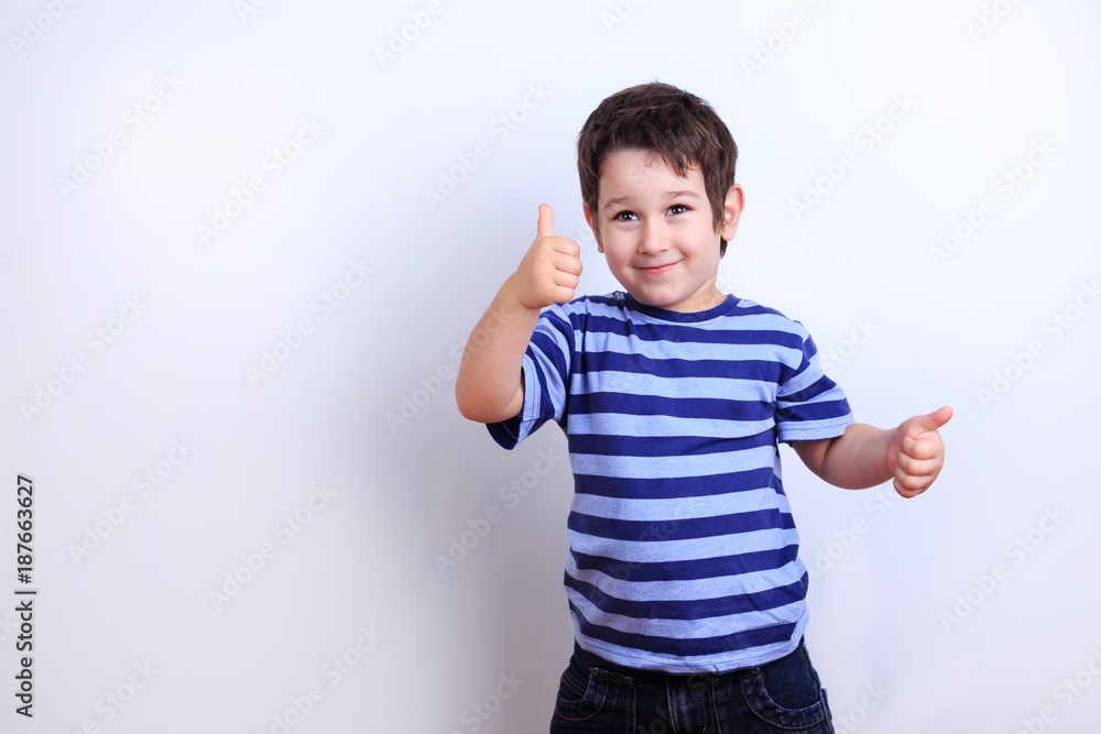 Cute happy boy showing thumbs up, studio shoot on white. Emotions, feelings, states of mind, childhood concept Cute happy boy showing thumbs up, studio shoot on white. Emotions, feelings, states of mind, childhood concept