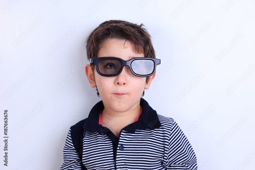 Happy smiling boy looking through sunglasses, studio shoot on white. Children, fashion and lifestyle concept Happy smiling boy looking through sunglasses, studio shoot on white. Children, fashion and lifestyle concept