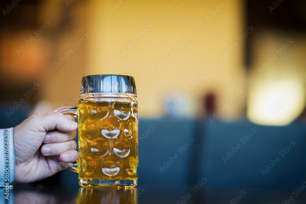 Men Hand with glass mug of golden Freshly filled beer. Real scene in bar, pub. Beer culture, Craft brewery, uniqueness beer grades, meeting of low alcohol beverage lovers Men Hand with glass mug of golden Freshly filled beer. Real scene in bar, pub. Beer culture, Craft brewery, uniqueness beer grades, meeting of low alcohol beverage lovers