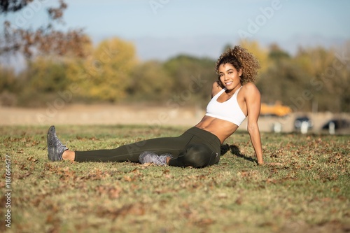 Obraz na plátně Young lady in green tights posing and stretching in warn sun