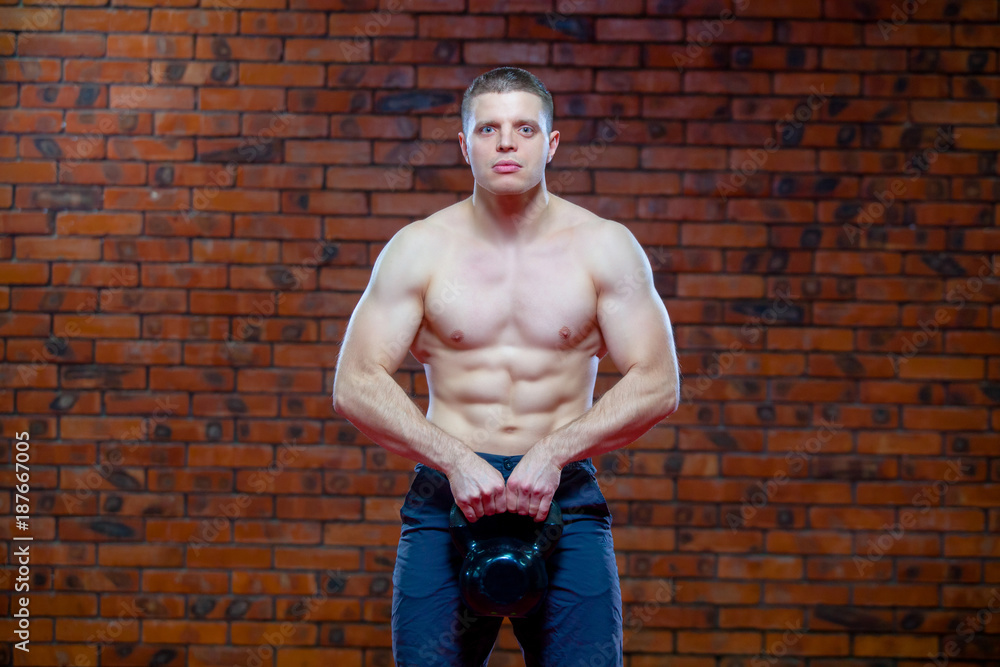 Strong young man swinging a kettlebell on dark background. Strength and ...