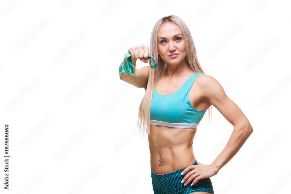 Athletic slender woman holding a measuring tape in the fist of her hand. The concept of will power, purposefulness. Athletic slender woman holding a measuring tape in the fist of her hand. The concept of will power, purposefulness.