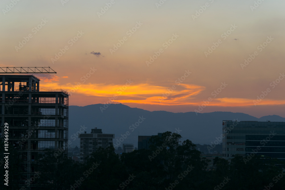 Construction of building between trees Guatemala City, silhouette at sunset.