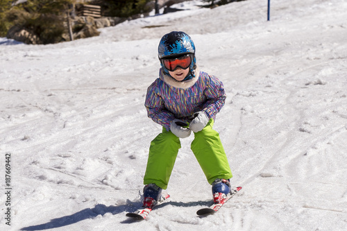 Girl on skis in soft snow on a sunny day in the mountains