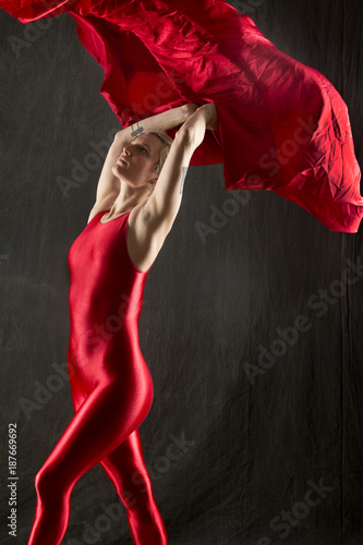 Fototapeta Naklejka Na Ścianę i Meble -  Young woman in red unitard under red fabric in studio.