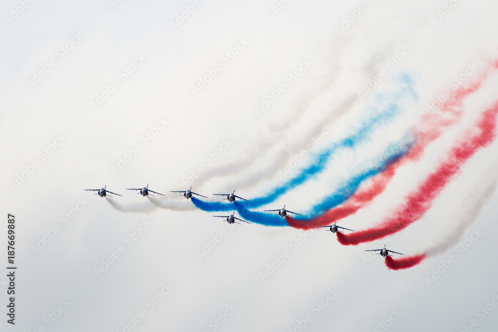 Eight aircraft at the air show demonstrate aerobatics figures and produce a multi-colored white blue red smoke - obrazy, fototapety, plakaty 