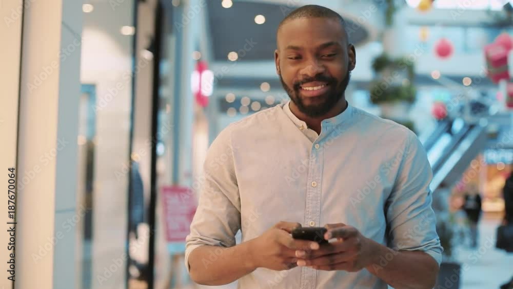 Portrait happy african american young man walking using phone in shopping center smiling christmas happiness internet face technology close up black telephone cute mobile holding slow motion Portrait happy african american young man walking using phone in shopping center smiling christmas happiness internet face technology close up black telephone cute mobile holding slow motion