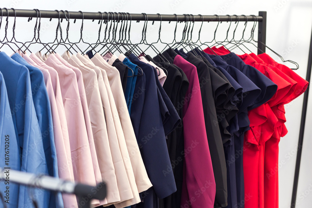 Obraz premium colorful women's dresses and other clothes on hangers in a retail shop. Fashion and shopping concept