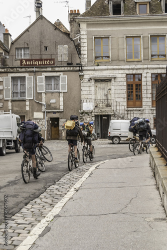 French school age boys on their bicycles with backpacks riding down a street in Chartres