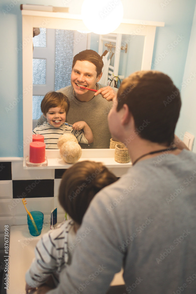 Young father with his son brushing teeth