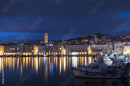 Night view of Oneglia, Imperia. Typical village of the Ligurian coast, Italy, mediterranean sea, with fishing and pleasure boats moored in the harbor.