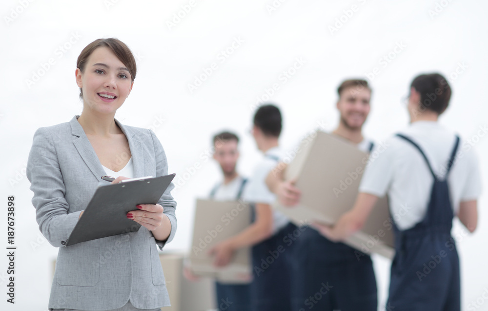 Woman manager holding clipboard on blurred background with mover Woman manager holding clipboard on blurred background with mover