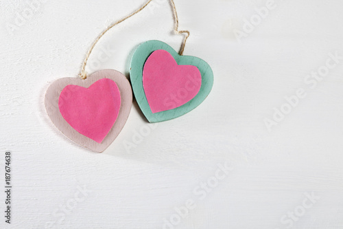 Two wooden hearts hang on a white wooden wall © elenarostunova