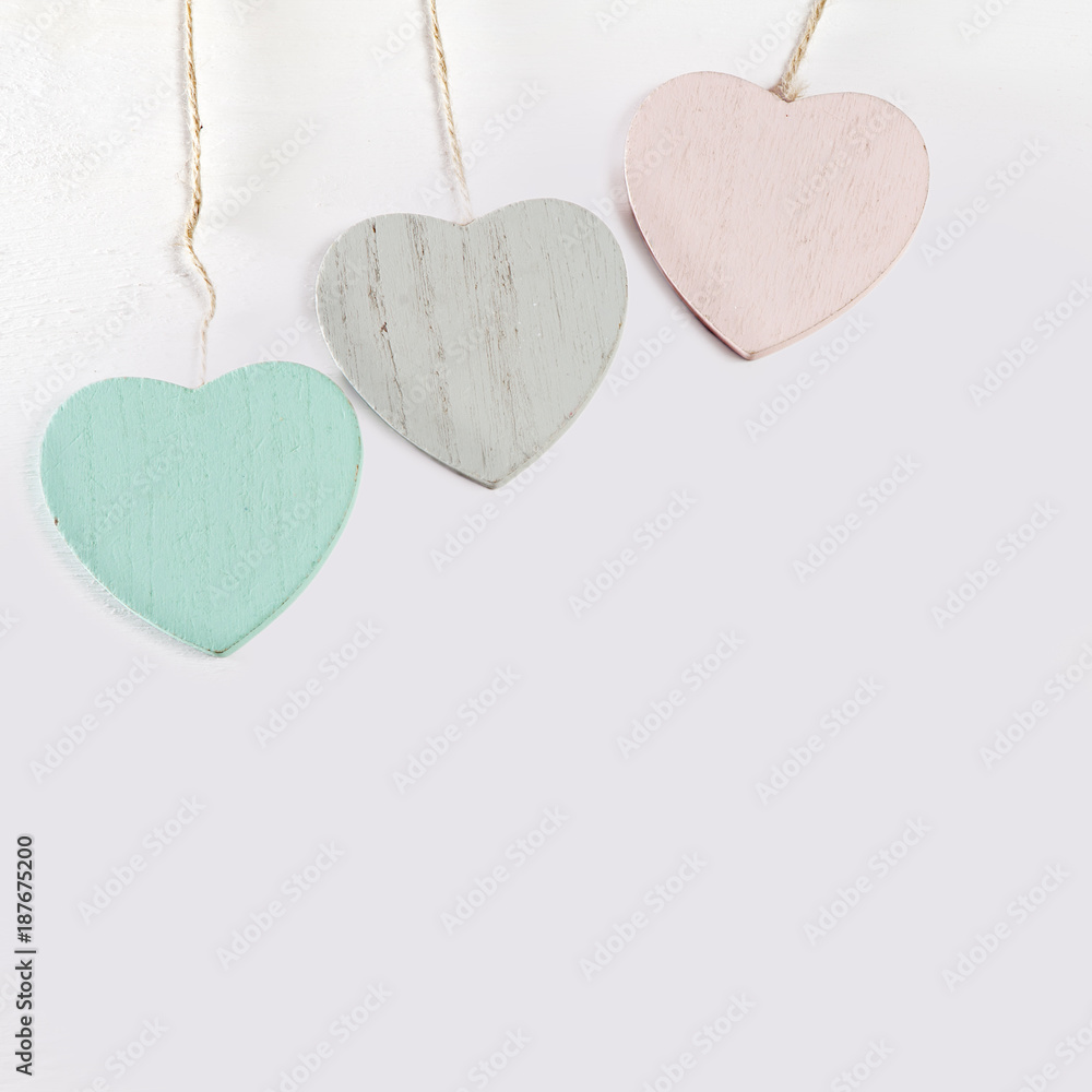 Obraz premium Three wooden hearts hang on a white wooden wall