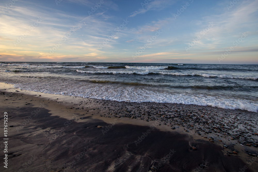 Scenic Seashore Background. Wide sandy beach with waves crashing on the shore during sunset at Whitefish Point in the Upper Peninsula of Michigan.