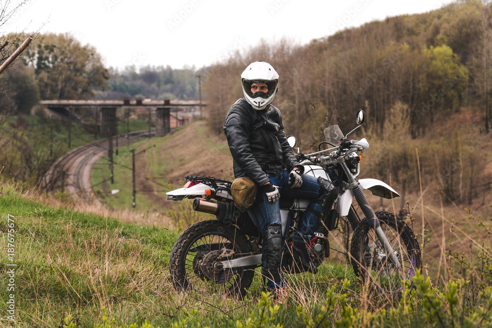 Man in dual sport helmet with backpack, enduro off road motorcycle on the forest road during sunrise. travel freedom concept Man in dual sport helmet with backpack, enduro off road motorcycle on the forest road during sunrise. travel freedom concept