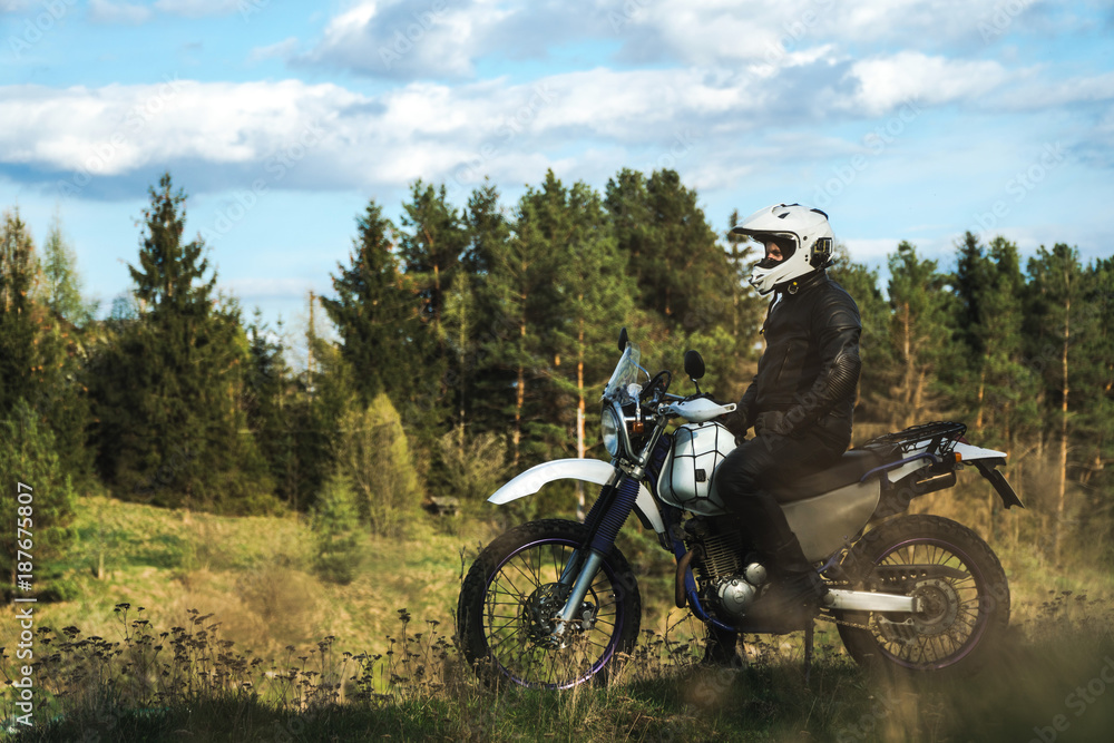 Biker man stands on the road forest and looks into the distance enduro Biker man stands on the road forest and looks into the distance enduro