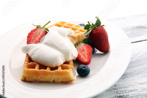 Plate of belgian waffles with whipped cream and fresh berries