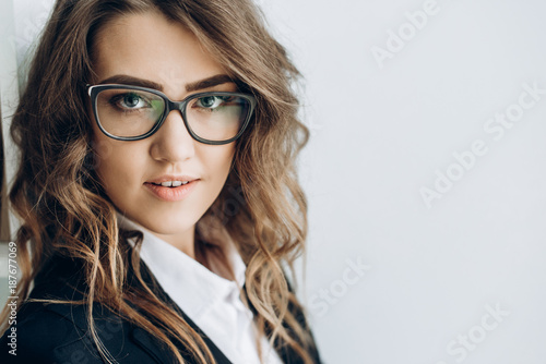 Portrait of a beautiful young girl in a business suit and glasses