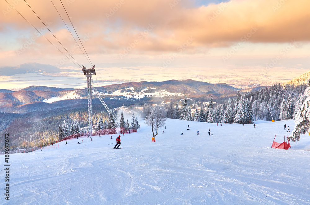 Skiers and snowboarders enjoy the ski slopes in Poiana Brasov winter resort on a sunny winter Skiers and snowboarders enjoy the ski slopes in Poiana Brasov winter resort on a sunny winter