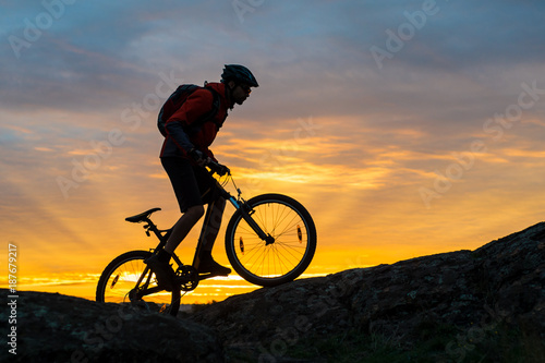 Fototapeta Naklejka Na Ścianę i Meble -  Cyclist in Red Riding the Bike on Autumn Rocky Trail at Sunset. Extreme Sport and Enduro Biking Concept.
