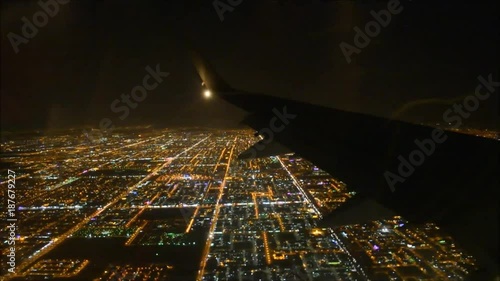 Impressive aerial flight view from passenger air plane wing on brigh night big city light illumination in dark black sky
