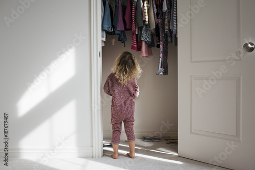 Rear view of girl standing at closet photo