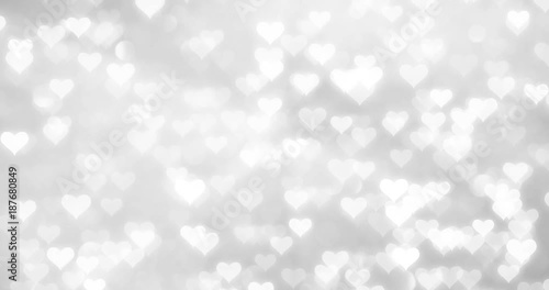 Shiny white hearts movement on blurry silver bokeh reflection background. 