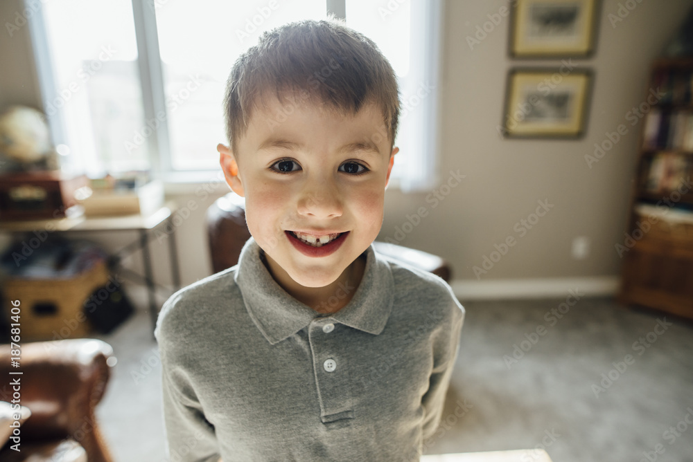 Portrait of smiling boy standing against window at home Portrait of smiling boy standing against window at home